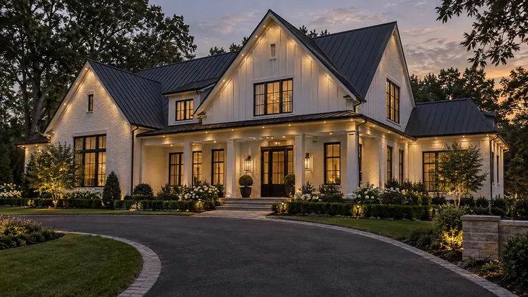 White modern farmhouse with permanent warm white lights beneath its gables
